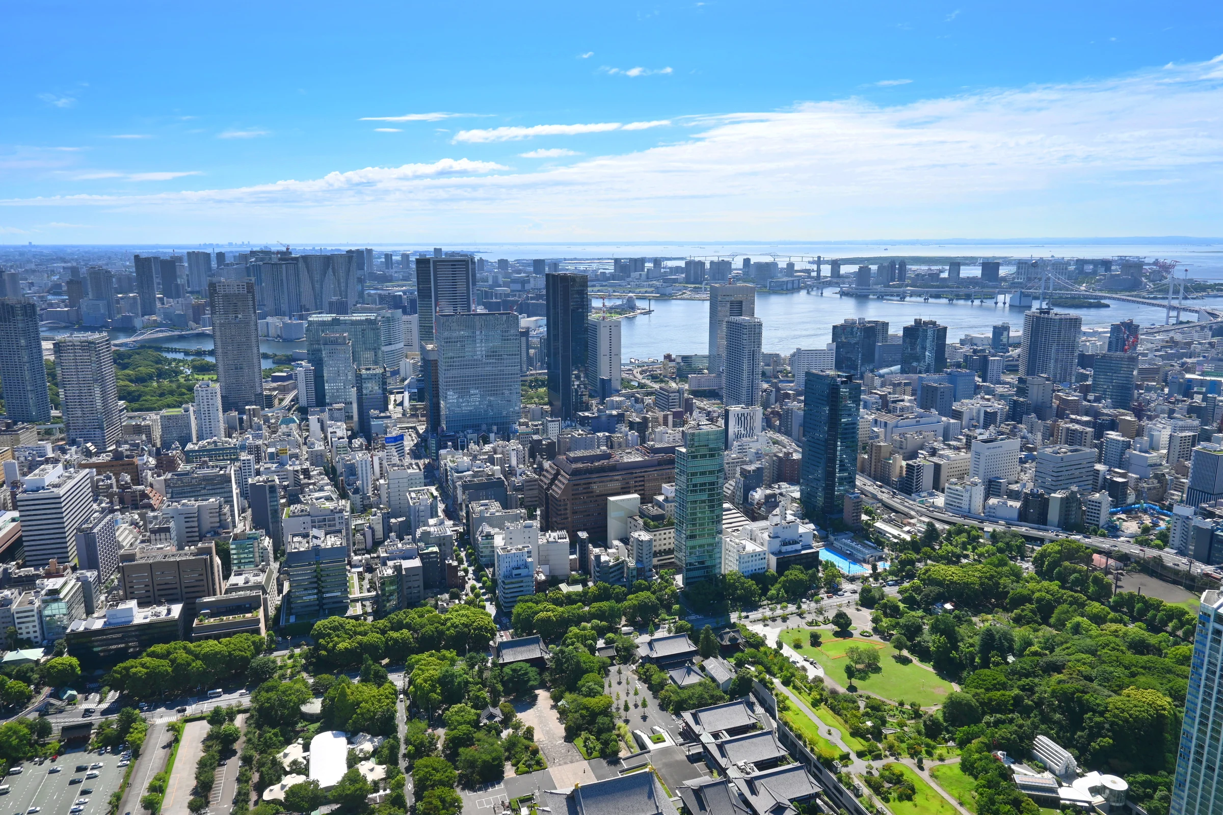 青空の下に広がる湾岸の街並みと緑地。イメージ写真